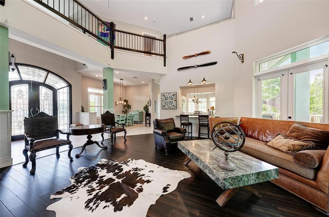 living room featuring a towering ceiling, french doors, hardwood / wood-style floors, and a healthy amount of sunlight