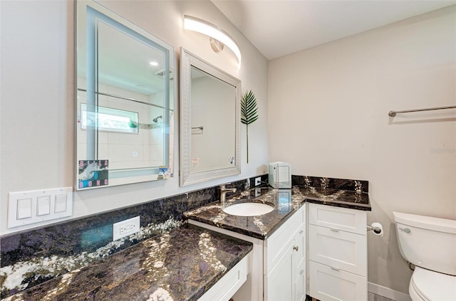 bathroom with vanity, toilet, and tiled shower