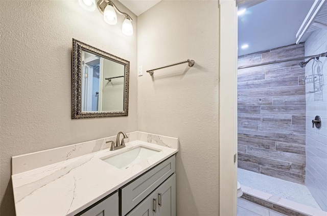 bathroom with vanity, toilet, and tiled shower