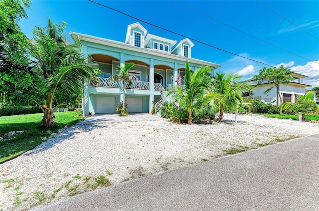 raised beach house featuring covered porch and a garage