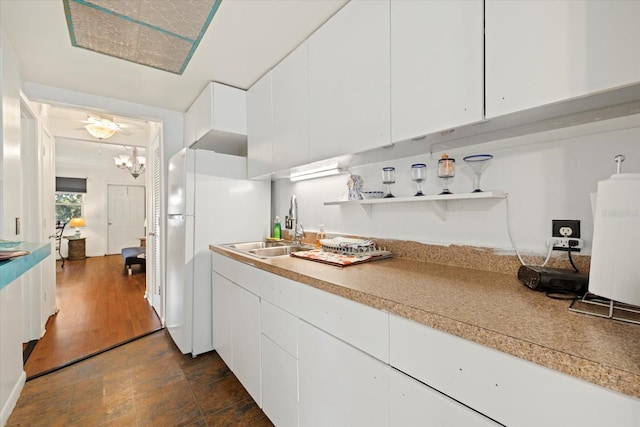 kitchen with white cabinets, sink, white fridge, a notable chandelier, and dark hardwood / wood-style flooring