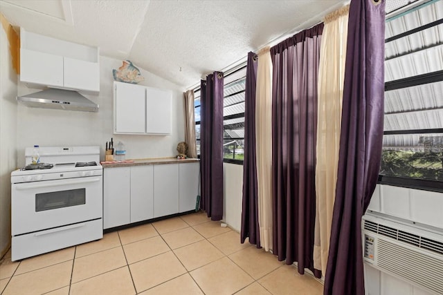 kitchen with white cabinets, lofted ceiling, light tile patterned floors, white gas range, and ventilation hood