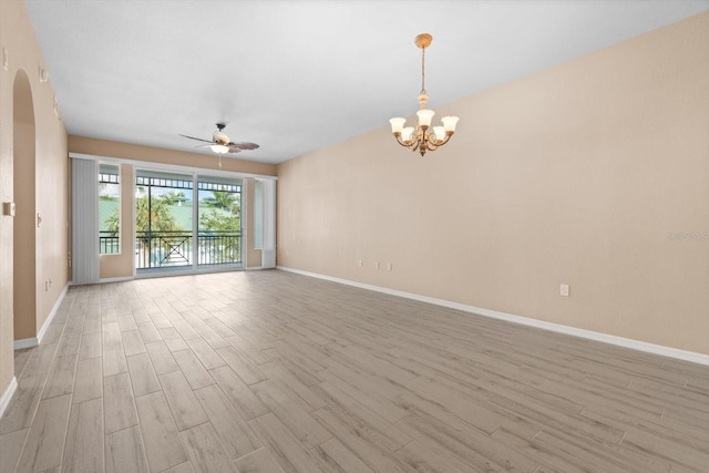 unfurnished room with arched walkways, light wood-style flooring, baseboards, and ceiling fan with notable chandelier