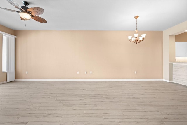 empty room with light wood-style flooring, baseboards, and ceiling fan with notable chandelier