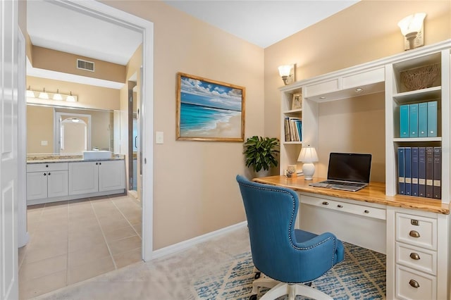 carpeted home office with built in desk and sink