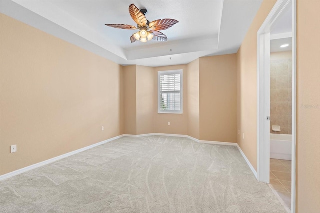 carpeted empty room featuring ceiling fan and a tray ceiling