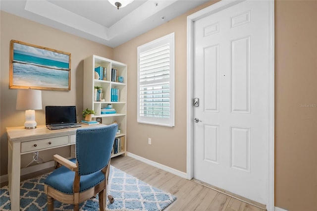 office featuring light hardwood / wood-style floors and a tray ceiling