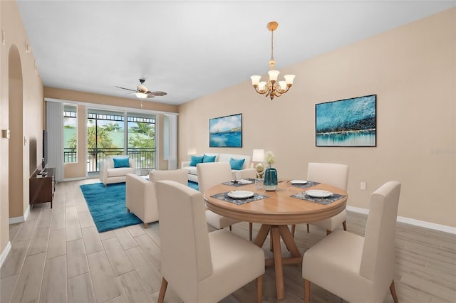 dining space with light wood-type flooring and ceiling fan with notable chandelier