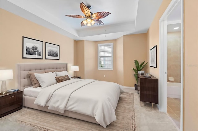 tiled bedroom featuring ensuite bathroom, a raised ceiling, and ceiling fan