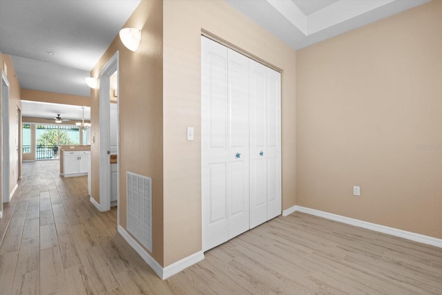 hallway featuring light wood-style flooring, visible vents, and baseboards