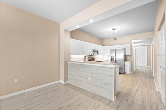 kitchen featuring a peninsula, white cabinetry, appliances with stainless steel finishes, and light countertops