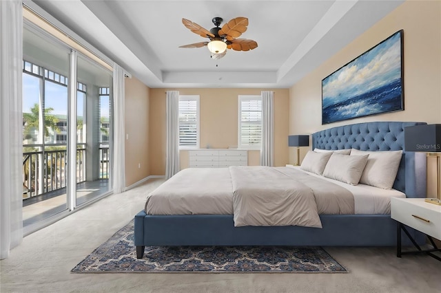 bedroom with ceiling fan, light carpet, baseboards, access to outside, and a tray ceiling