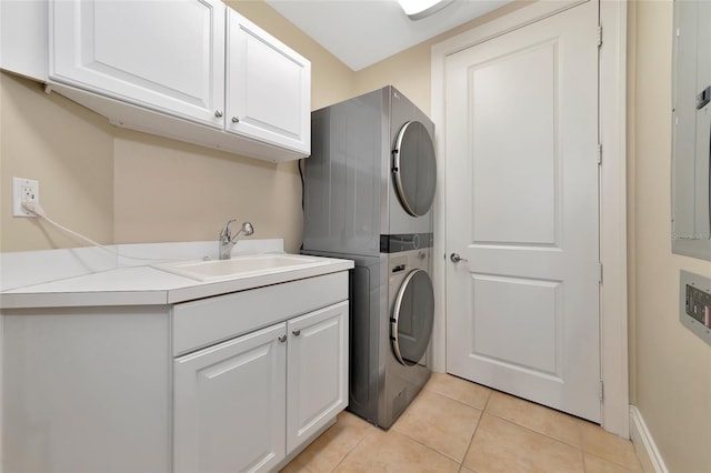 clothes washing area featuring cabinets, light tile patterned flooring, stacked washer / dryer, and sink