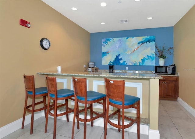 bar with light tile patterned floors and light stone counters