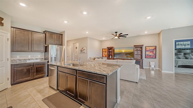 kitchen with ceiling fan, sink, stainless steel appliances, a center island with sink, and dark brown cabinets