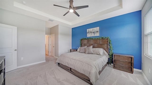 carpeted bedroom with a tray ceiling and ceiling fan