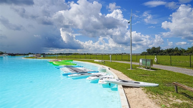 view of swimming pool with a yard and a water view