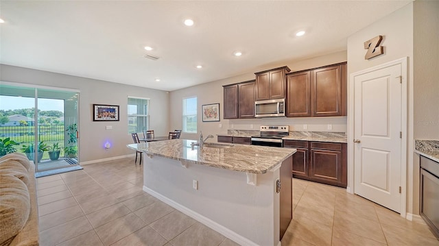 kitchen with a center island with sink, dark brown cabinets, sink, and appliances with stainless steel finishes