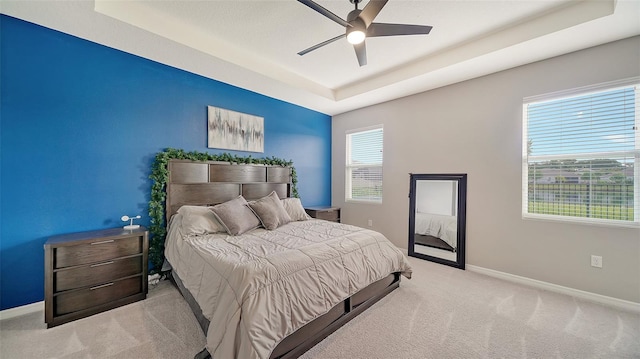 bedroom featuring a tray ceiling, ceiling fan, and light carpet