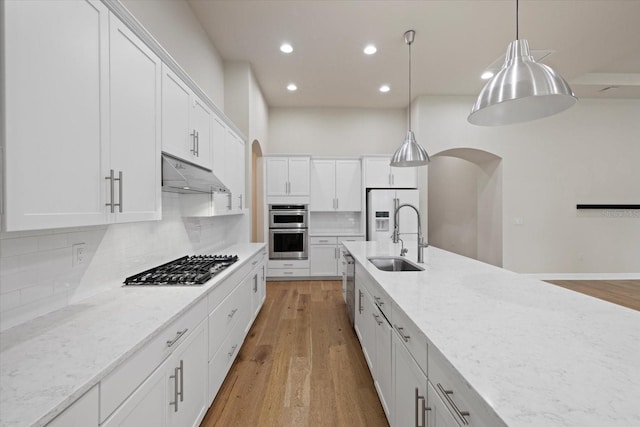 kitchen with white cabinetry, light stone counters, pendant lighting, light wood-type flooring, and sink