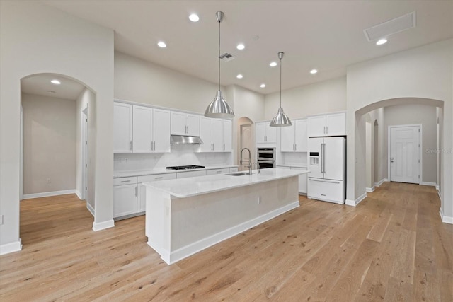 kitchen featuring white cabinetry, white fridge with ice dispenser, light hardwood / wood-style flooring, a kitchen island with sink, and sink