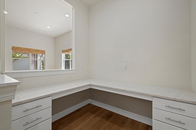 unfurnished office featuring built in desk, plenty of natural light, and dark hardwood / wood-style flooring