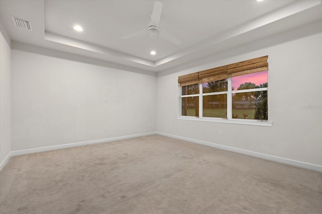 spare room featuring carpet flooring, a tray ceiling, and ceiling fan