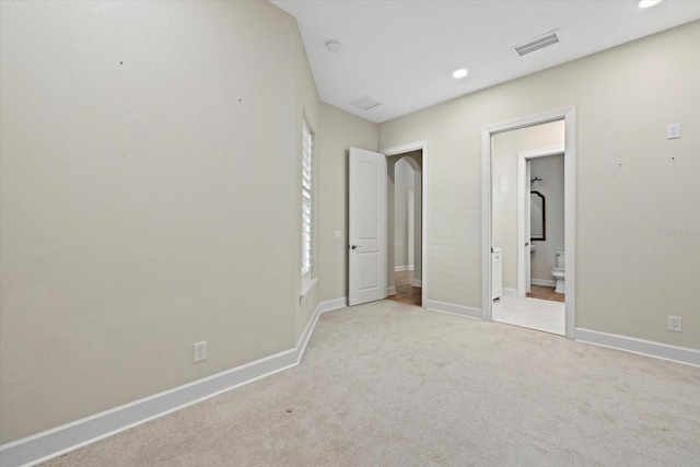 unfurnished bedroom featuring ensuite bathroom and light colored carpet