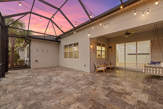 exterior space with glass enclosure, ceiling fan, and a patio