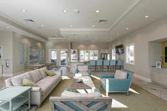 living room featuring a wealth of natural light, a tray ceiling, and crown molding