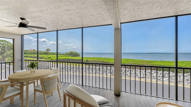 sunroom / solarium with ceiling fan and a water view