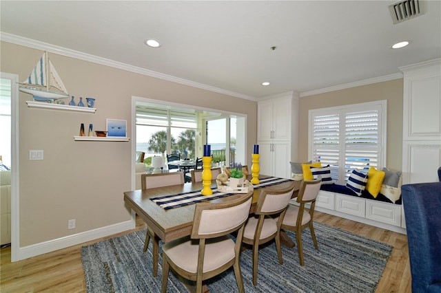 dining space featuring crown molding and light hardwood / wood-style flooring