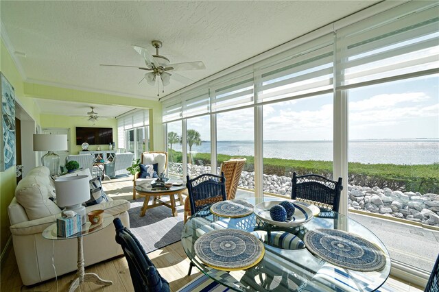 sunroom with ceiling fan, a water view, and a wealth of natural light