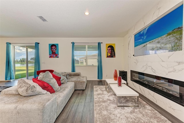 living room featuring a premium fireplace, hardwood / wood-style flooring, and a textured ceiling