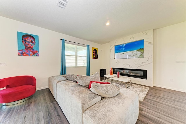 living room featuring a textured ceiling, hardwood / wood-style flooring, and a fireplace