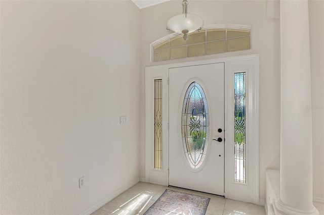 foyer featuring light tile patterned flooring, a high ceiling, and decorative columns