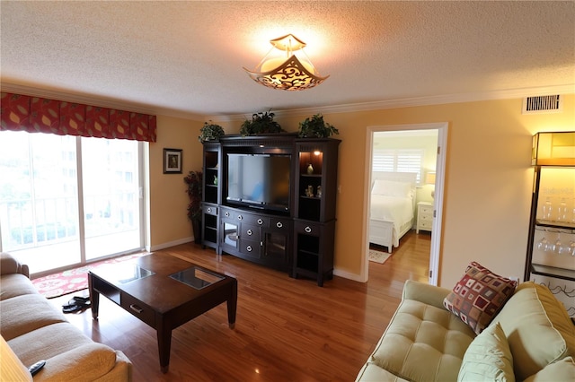 living room with a textured ceiling, crown molding, and hardwood / wood-style floors