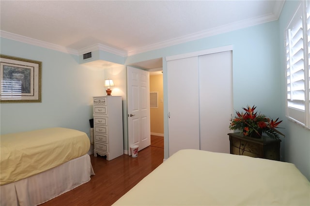 bedroom with ornamental molding, a closet, and dark hardwood / wood-style floors