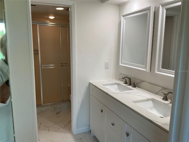 full bathroom featuring double vanity, a stall shower, marble finish floor, and a sink