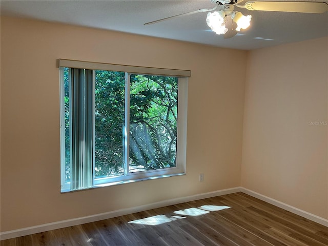 spare room featuring baseboards, wood finished floors, and a ceiling fan
