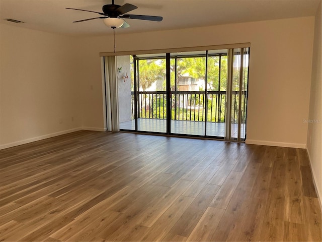unfurnished room featuring a ceiling fan, visible vents, wood finished floors, and baseboards