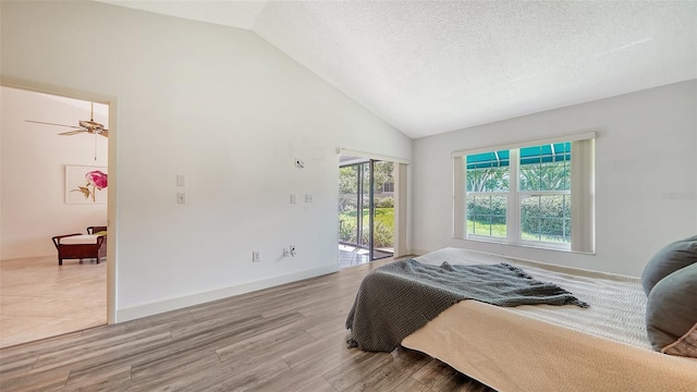 bedroom featuring a textured ceiling, light wood-type flooring, access to exterior, and high vaulted ceiling