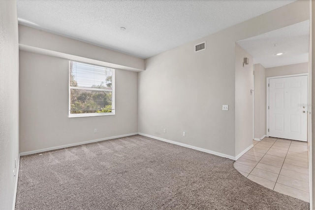 spare room with light carpet and a textured ceiling