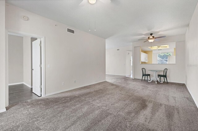 unfurnished living room with dark carpet and ceiling fan