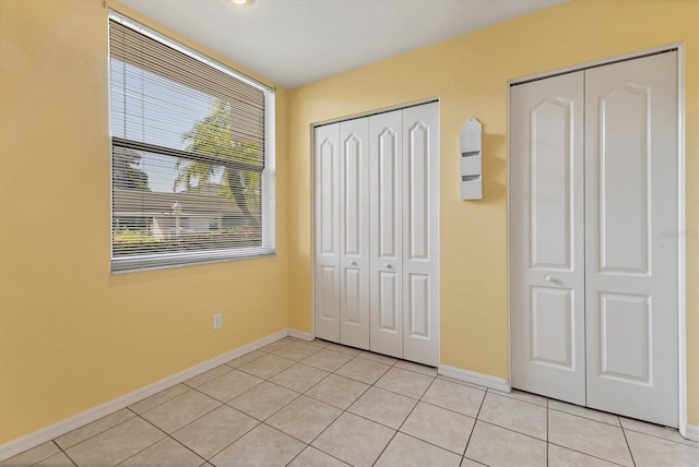 unfurnished bedroom featuring two closets and light tile patterned floors