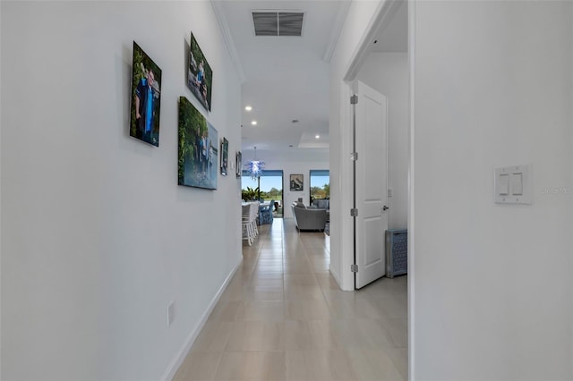 hallway with ornamental molding and light tile patterned flooring