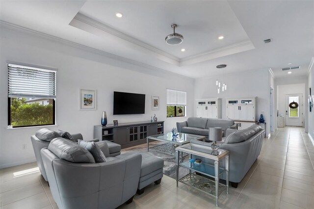 living room featuring crown molding, a healthy amount of sunlight, a tray ceiling, and light tile patterned floors