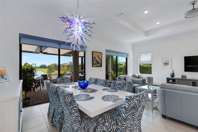 dining area with light tile patterned flooring, a tray ceiling, and ornamental molding