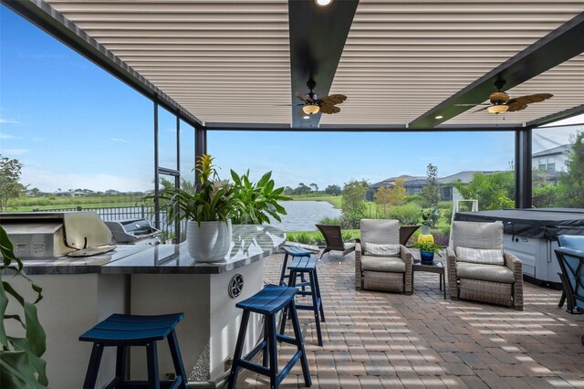 view of patio with an outdoor bar, exterior kitchen, a water view, ceiling fan, and grilling area