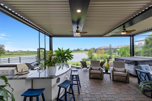 view of patio featuring a water view, ceiling fan, and a bar